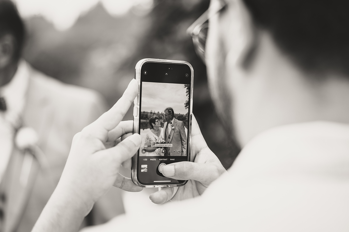 Une photo prise du téléphone lui même en train de prendre en photo les mariés. Une photo décalée de mariage.