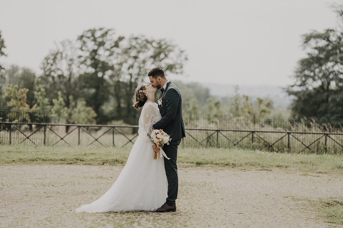 Mariés s'embrassant dans un cadre naturel champêtre